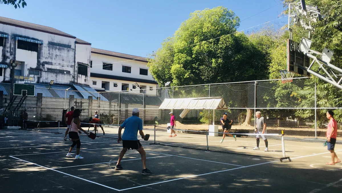 Doubles game on a Chiang Mai court framed by trees