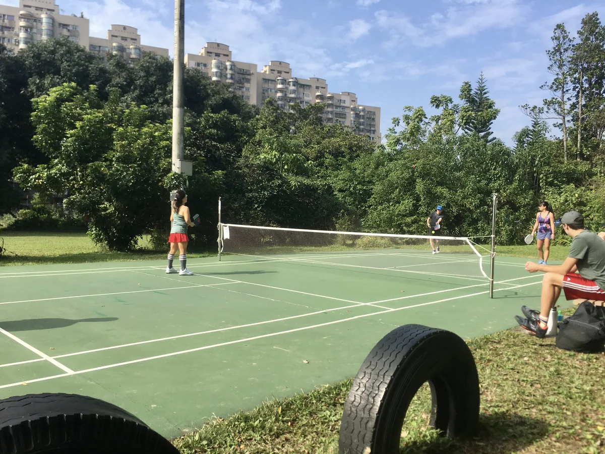 Daytime open play on a tree-lined Taipei park court